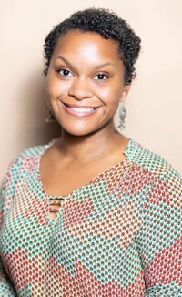 a black woman smiling in a colorful top